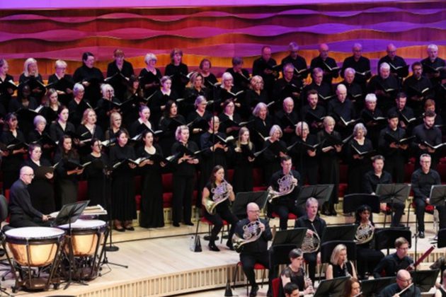 Members of the orchestra and choir performing on stage wearing all black