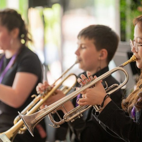 Members of Youth Brass Band dressed in all black playing their trumpets