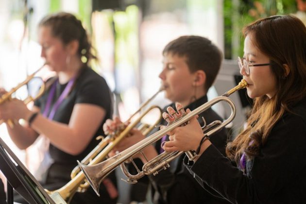 Members of Youth Brass Band dressed in all black playing their trumpets