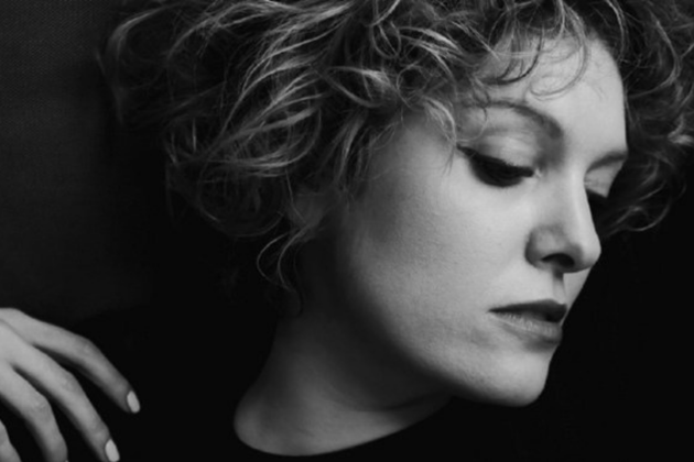 Black and white image of Jenny Daviet, who has short curly hair, looking off to the right
