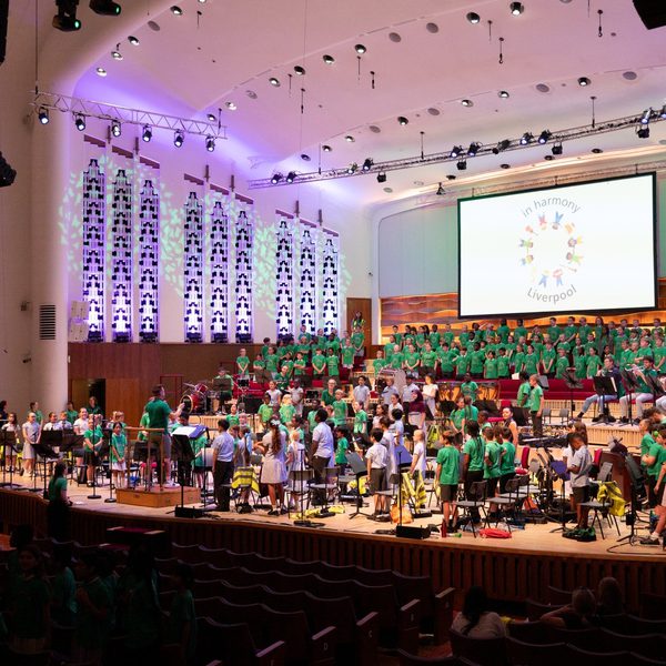 Members of In Harmony ensembles stood on stage wearing green t-shirts