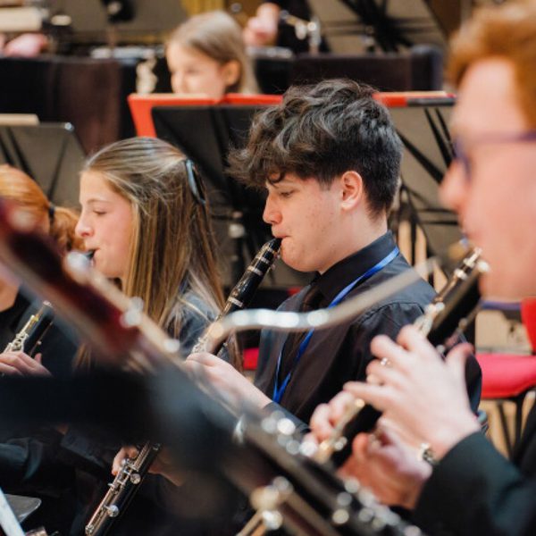 Members of the Youth Orchestra woodwind section, wearing all black and playing their instruments