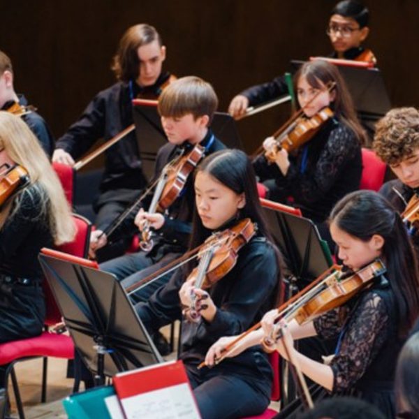 Members of the Youth Orchestra string section playing their instruments and wearing all black