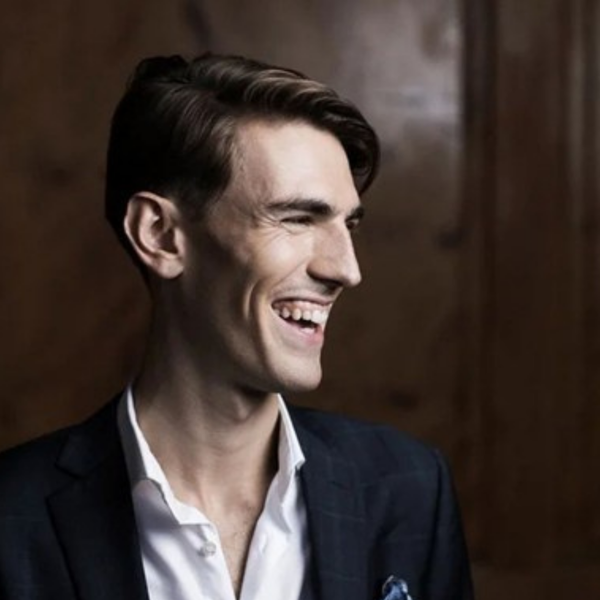Jonathan Eyres, a white man with short brown hair, wearing a white shirt and black jacket and laughing