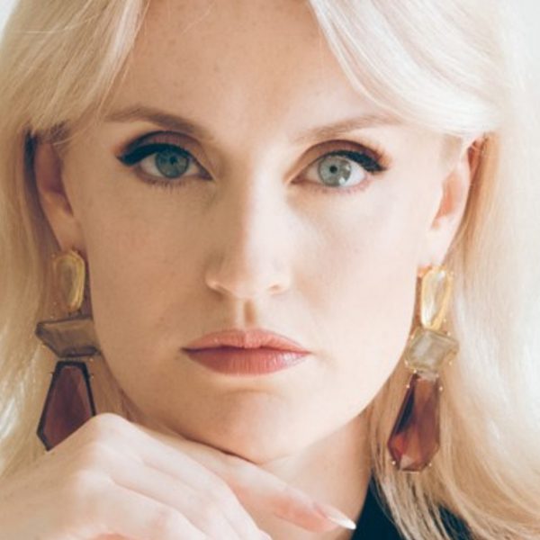 Sarah Brady, a white woman with long blonde hair, leaning on her hand looking directly at the camera
