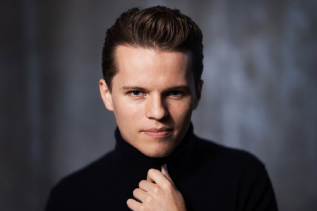 Adam Hickox, a white man with short brown hair, wearing a black turtleneck and looking at the camera