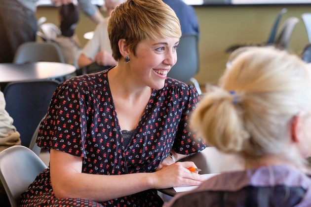Claire Henry, a white woman with short blonde hair, wearing a polka dot dress and smiling at someone off camera