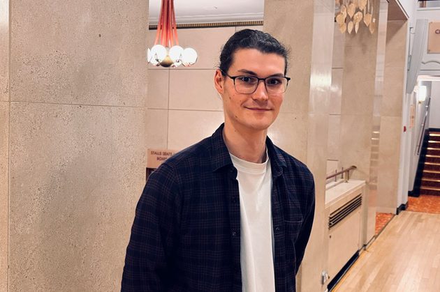 Rob Hughes wearing a white shirt with dark blue jacket, smiling at the camera and wearing dark glasses